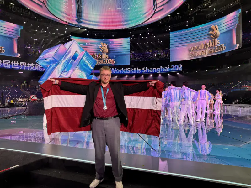 Krišjānis Klāvs Kantāns ar Latvijas karogu un medaļu WorldSkills Shanghai 2026 konkursā
